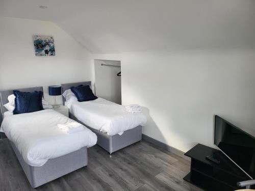 a room with two beds and a flat screen tv at Vetrelax Southend Apartment in Westcliff-On-Sea