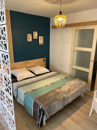 Gîte des Restanques في جراس: غرفة نوم بسرير وجدار ازرق