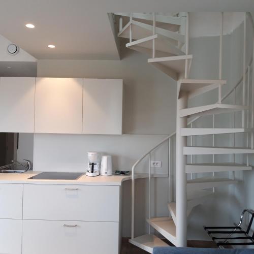 a kitchen with white cabinets and a spiral staircase at B&B 't Hof van Spiere in Spiere
