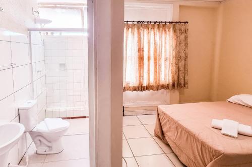 uma casa de banho com uma cama, um WC e um chuveiro em ALVORADA PALACE HOTEL em Bauru