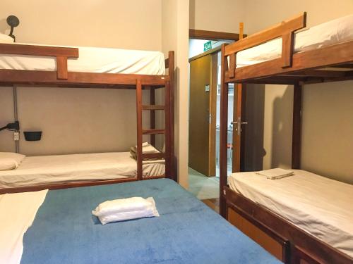 a room with three bunk beds and a blue bed at MADÁ hostel in Sao Paulo