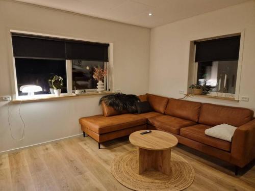 a living room with a brown couch and a table at New flat with hot tub - No3 in Oyndarfjørður