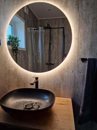 a bathroom with a sink and a round mirror at New flat with hot tub - No3 in Oyndarfjørður