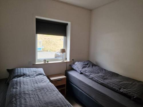 two beds in a room with a window at New flat with hot tub - No3 in Oyndarfjørður