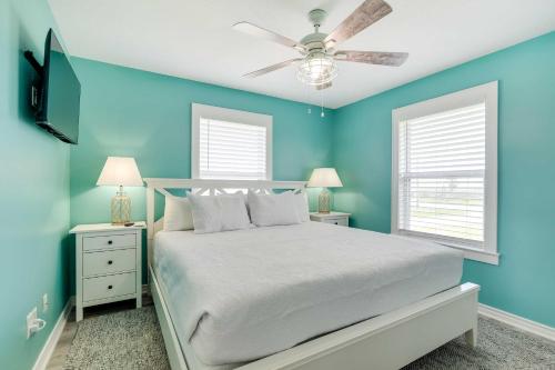a blue bedroom with a bed and a ceiling fan at Walk to Shore Home with Deck in Crystal Beach! in Crystal Beach