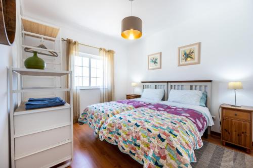 Un dormitorio con una cama con una colcha colorida. en Sweet Home Sagres, en Sagres