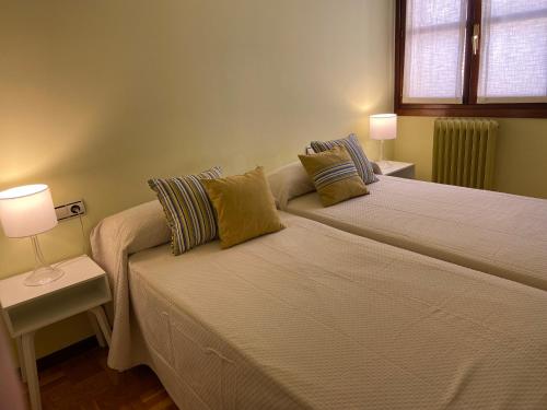 2 camas en un dormitorio con 2 lámparas y una ventana en Apartamento Horia, en Viana