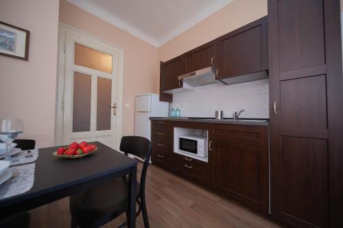 a kitchen with wooden cabinets and a table with a bowl of fruit at Apartman Bianca the Best in Rijeka