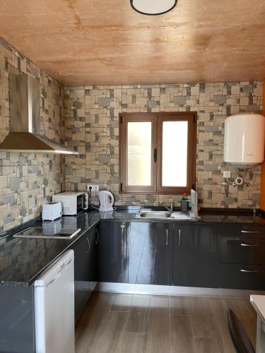 a kitchen with black counter tops and a window at casa caminho da praia in Porto da Cruz