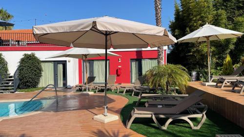 Villa 3 Caparica - Lisbon Gay Beach Resort في تشارنكه: فناء فيه كراسي ومظلات بجانب مسبح