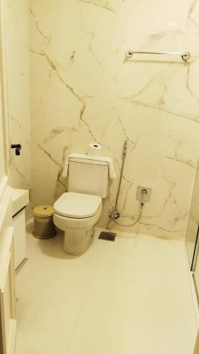 a bathroom with a toilet and a marble wall at Center Suiço Flats in Campos do Jordão