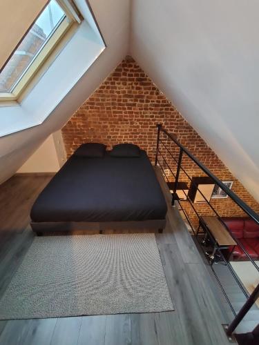 a loft bed in a room with a brick wall at Le Cosy in Bohain-en-Vermandois