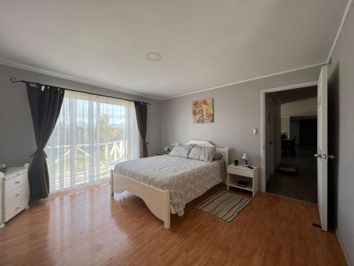 1 dormitorio con cama y ventana grande en Casa de campo, en Curacautín