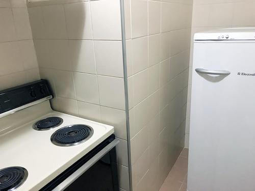 a small kitchen with a stove and a refrigerator at Center Suiço Flats in Campos do Jordão