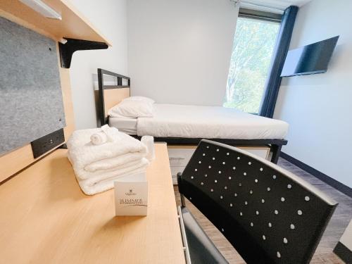 um quarto com duas camas, uma mesa e uma cadeira em Queen's University Residence em Kingston