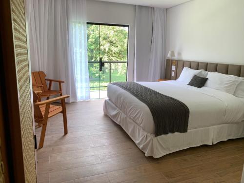 a bedroom with a bed and a chair and a window at Pousada Menino de Ouro in Penedo