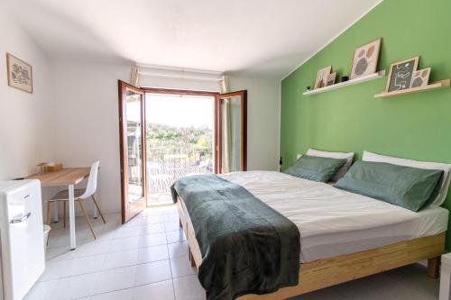 ein Schlafzimmer mit einem Bett mit einer grünen Wand in der Unterkunft Maeva Guesthouse in Puegnago