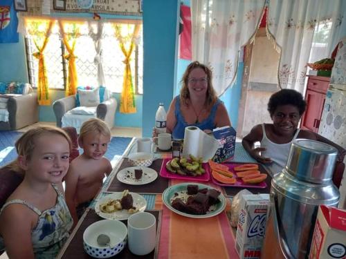 un grupo de personas sentadas en una mesa con comida en Save's Homestay en Nadi