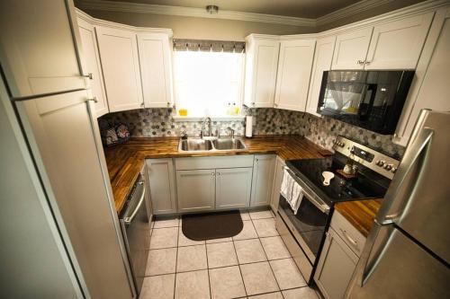 a kitchen with white cabinets and a sink at Bristow Blue - Lake front with Boat Ramp Access!! in Canadian