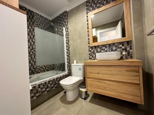 ein Badezimmer mit einem WC, einem Waschbecken und einem Spiegel in der Unterkunft Hercules Town BY Oktheway in A Coruña