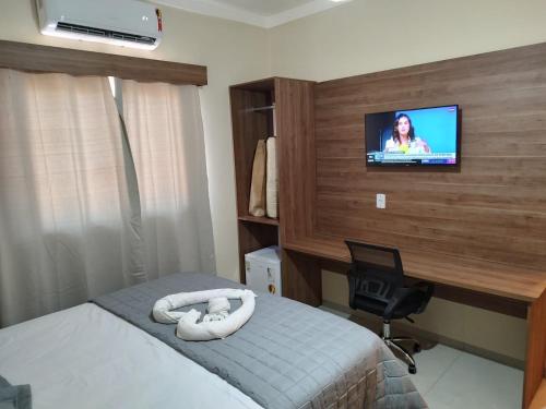 Hotel Vale Do Ivinhema في Bataiporã: غرفة نوم بسرير وتلفزيون على جدار