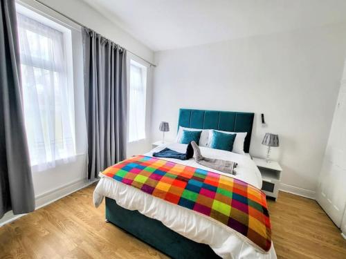 een slaapkamer met een groot bed en een kleurrijke deken bij Comfortable House near Etihad - Stay Sleep Rest in Manchester