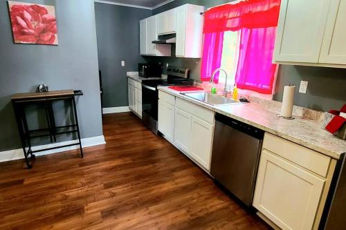 eine Küche mit weißen Schränken und Holzböden in der Unterkunft Comfortable 3 bedroom home with private parking! in Elmira