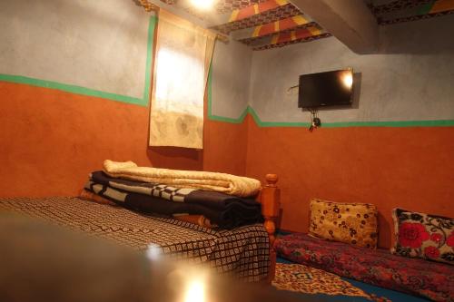 Cette chambre dispose d'un canapé et d'une télévision murale. dans l'établissement Tigmino Maison D'or, à Tafraout