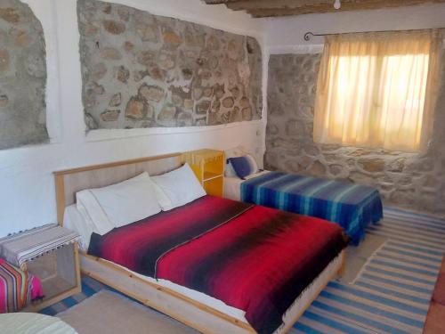 een kleine slaapkamer met een bed en een raam bij Gîte El houmar in Tanakoub