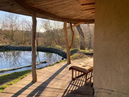 a wooden porch with a bench next to a river at Lehmhaus in Templin