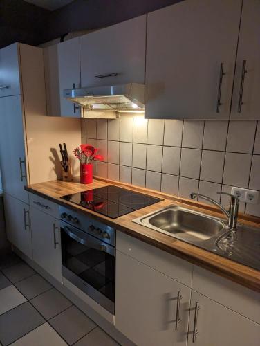 una cocina con armarios blancos y fregadero en Flensburg Zentrum 10 VH 2OG R en Flensburg