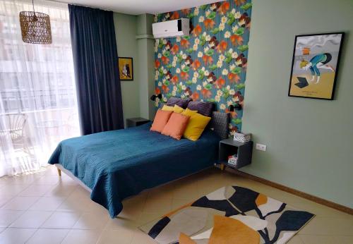 Dormitorio con cama azul y pared colorida en Apartment Daisy Grand Kamelia en Sunny Beach