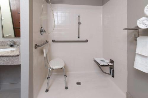 a bathroom with a shower and a chair in it at Best Western Dartmouth-New Bedford in North Dartmouth
