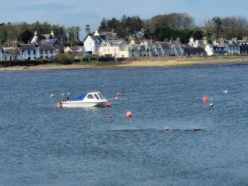a small boat in a large body of water with houses at Stunning Caravan Whithorn3 in Newton Stewart