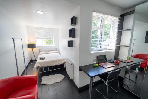 1 dormitorio con 1 cama y escritorio con ordenador portátil en Stylish Studio for short term near the City!, en Birmingham