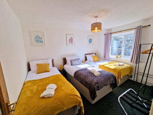 um quarto com 2 camas com lençóis amarelos e brancos em Spacious & comfy Home- very close to NEC Birmingham ,HS2 & Airport- Perfect for contractors & groups- free parking & Fast WiFi em Marston Green