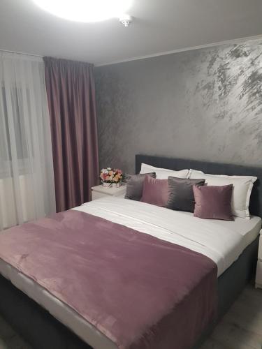 a bedroom with a large bed with purple and white pillows at GREY VILLAS in Călimăneşti
