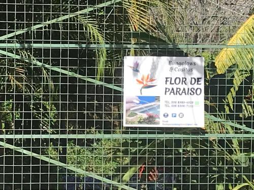 a sign on a wire fence with plants at FLOR DE PARAISO BUNGALOWS in Montezuma