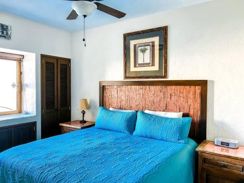a bedroom with a blue bed with a wooden headboard at Sandy Beach Princesa A103 Ocean Front Resort in Puerto Peñasco
