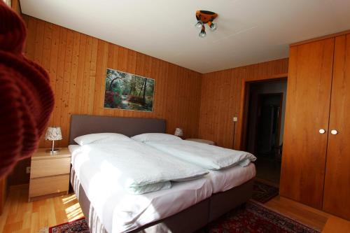 a large bed in a bedroom with wooden walls at Hotel-Restaurant Alpina in Innertkirchen