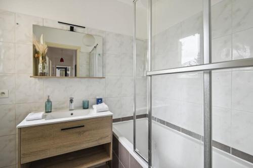 La salle de bains est pourvue d'une baignoire, d'un lavabo et d'une douche. dans l'établissement "Joie de vivre" - Parisian Spacious & Charming flat, à Asnières-sur-Seine