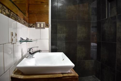 a white sink in a bathroom with black tiles at The Fox Hostel in Santiago