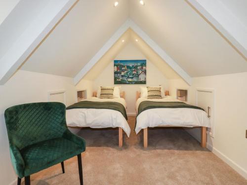 een slaapkamer op zolder met 2 bedden en een groene stoel bij Quay View in St Austell