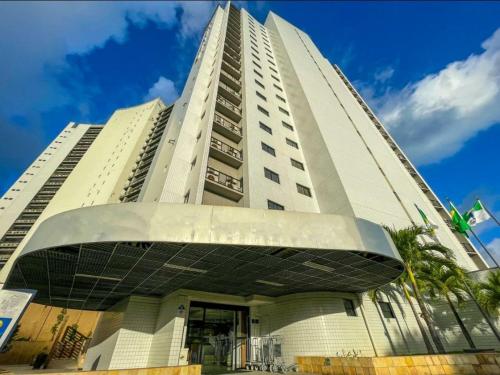 a tall white building with a building at Ponta Negra Flats Confort ACCOMMODATIONS AMAQ 18 andar in Natal