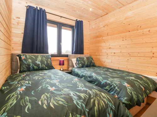 1 dormitorio con 2 camas en una cabaña de madera en The Lodge at Crossroads Farm en Bridgwater