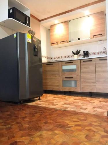 a kitchen with a stainless steel refrigerator and wooden cabinets at Aparta estudio de la panamericana in Pasto