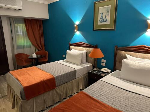 duas camas num quarto de hotel com paredes azuis em Gawharet Al Ahram Hotel em Cairo