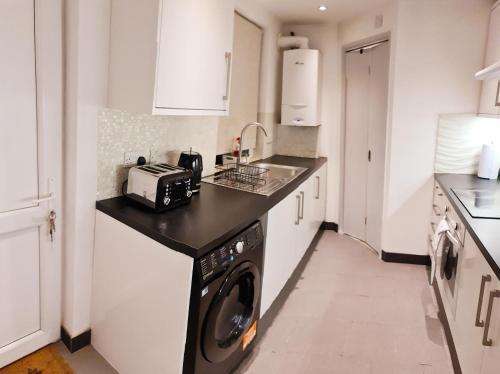une cuisine avec un lave-linge et un sèche-linge sur un comptoir dans l'établissement Maple House - Inviting 1-Bed Apartment in London, à Londres