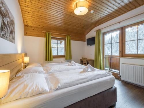 1 dormitorio con 1 cama grande y cortinas verdes en Alpensteinbock Saalbach L, en Saalbach Hinterglemm