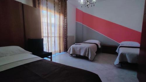 a bedroom with two beds and a red and white wall at Angis AffittaCamere in Pero